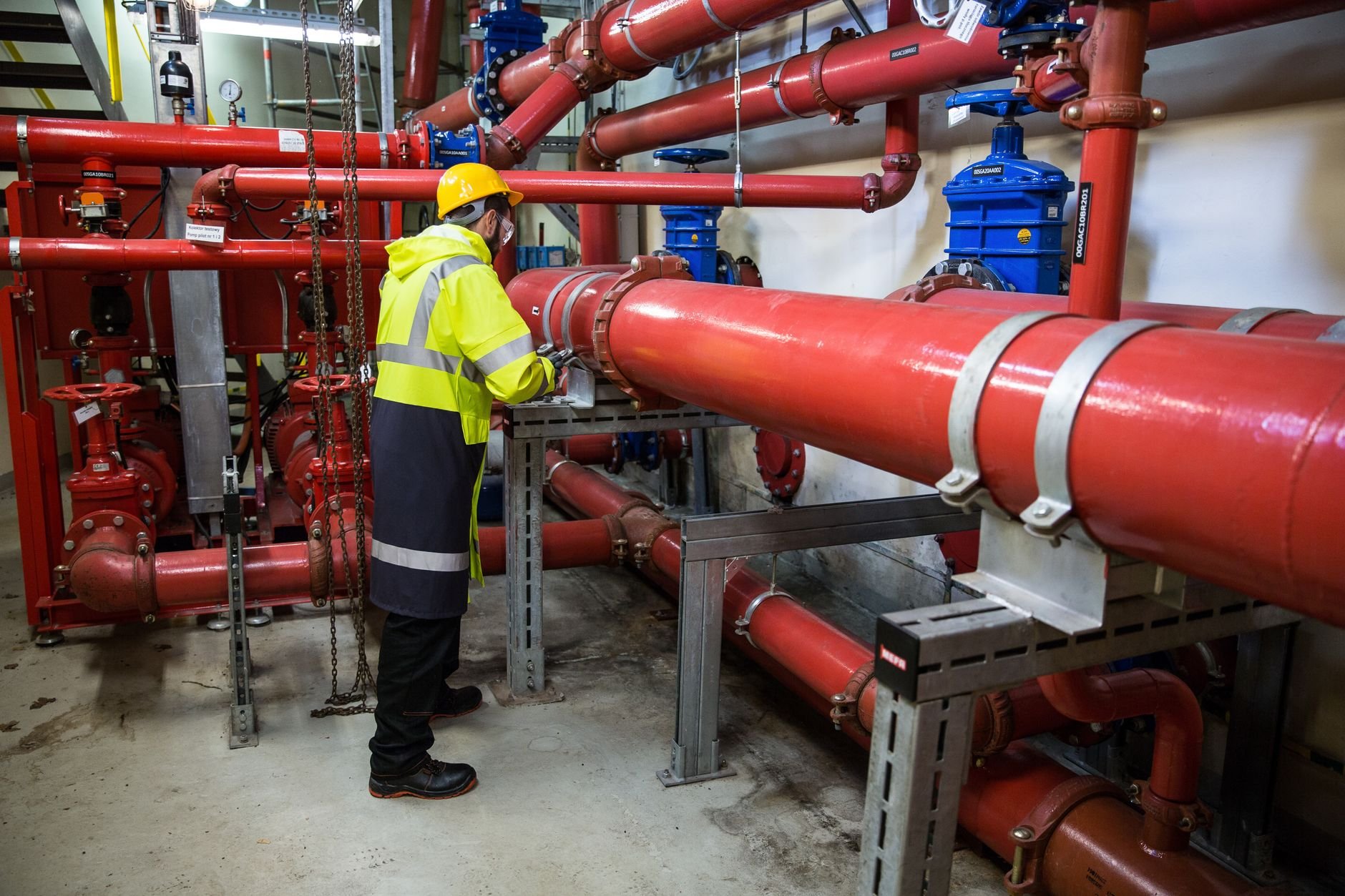 Engineer with safety gear inspecting industrial piping system